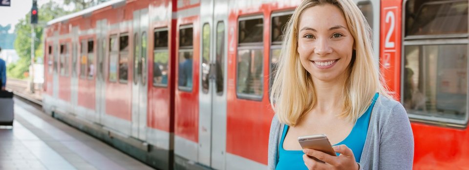 Junge Frau mit Handy am Bahnhof