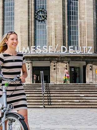 Junge Frau vor Bahnhof Köln Messe/Deutz